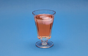 A stylish glass filled with a beverage rests on a blue background. This image is ideal for beverage marketing, cocktail recipes or lifestyle content.