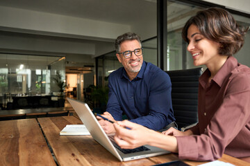 Happy young business woman manager showing project presentation to mature man client, investor or...