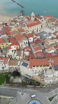 4K drone footage of Termoli in southern Italy, flying along the coast and showing historic buildings, a medieval tower, city walls and the Adriatic shoreline.
