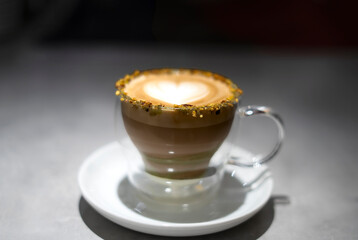 Pistachio latte art in double walled glass sitting on table