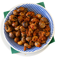On wooden table there is plate filled to brim with boiled snails. Shellfish snail cooked with minced meat and tomato dressing. Chopsticks are served with food. Isolated over white background