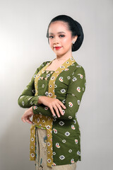 Indonesian woman in a traditional kebaya and batik, posing gracefully with a warm smile. She looks confident and elegant, embracing cultural heritage with beauty and charm.