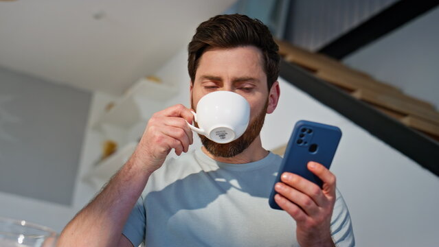 Morning guy reading cellphone message drinking coffee at home cuisine closeup - Powered by Adobe