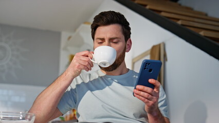 Breakfast man scrolling cellphone drinking coffee at cuisine closeup. Happy guy