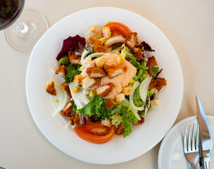 Appetizing Caesar salad with tomatoes, corn, olives and fried chicken