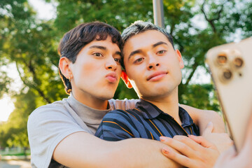 Gay latin couple hugging taking a selfie at sunset embracing, gen z