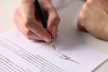 Man putting signature on document at table, closeup