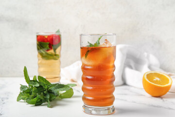 Fototapeta premium Glasses of ice tea with orange and strawberry on white background