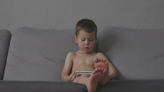 Young boy enjoys handheld console on couch innocence of childhood and excitement of video games. Boy playing on portable gaming console while seated on sofa delight of childhood world of young gamer