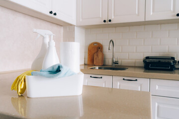 Pristine white kitchen with cleaning supplies on countertop