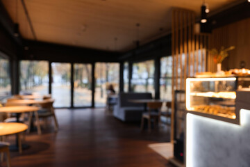 Blurred view of stylish restaurant with large windows and comfortable furniture. Interior design