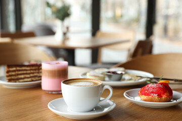 Aromatic coffee and delicious desserts served on wooden table in cafe