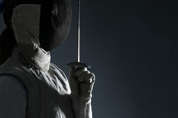 Fencer with epee on gray background, space for text