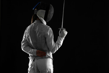 Fencer with epee on black background, space for text