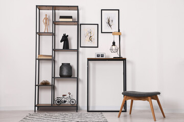 Shelving unit with different home decor and chair near white wall indoors