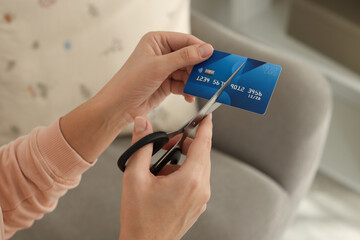 Woman cutting plastic credit card indoors, closeup
