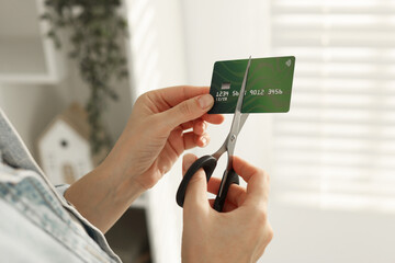 Woman cutting plastic credit card indoors, closeup
