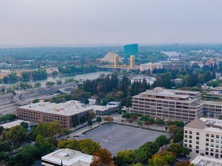 Sacramento, USA, cityscape view with the Tower Bridge over the Sacramento River. The image shows the city's architecture and infrastructure. The photo was taken during a hazy day.