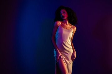 Elegant young woman in a fashionable gown posing in stunning neon colored lighting highlighting beauty