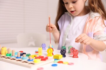 Motor skills development. Little girl playing with math game Fishing for Numbers at white table...