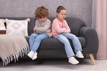 Resentful little brother and sister on couch at home. Family dispute