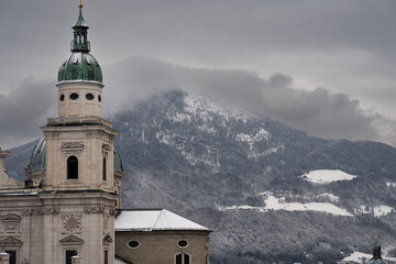 Cloudy Salzburg rooftop view, historical architecture, mountains, Austria winter.