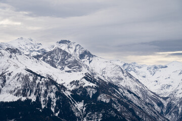 Cloudy January alpine landscape with mountains, trees, Austria.
