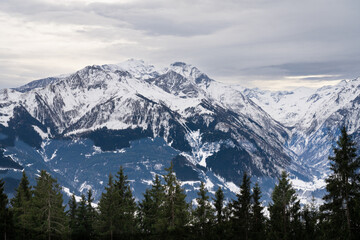 Cloudy January alpine landscape with mountains, trees, Austria.
