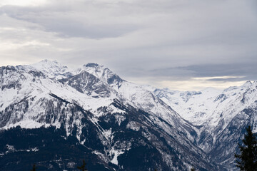 Cloudy January alpine landscape with mountains, trees, Austria.