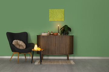 Interior of living room with armchair, commode and glowing pumpkins