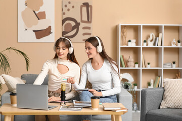 Young sisters in headphones with laptop recording podcast at home