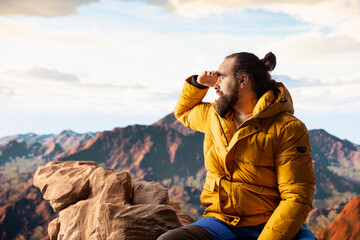 Trekker in warm clothing takes in the sweeping mountain scenic view, feeling the sense of freedom...