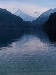 Fototapeta premium Majestic mountains reflect in tranquil lake under overcast sky at twilight