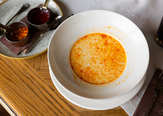 Small portion of traditional Bulgarian first course, shkembe chorba, is served in deep plate. Food is made from cows stomach, milk, and served with two types of hot spices based on garlic and pepper.
