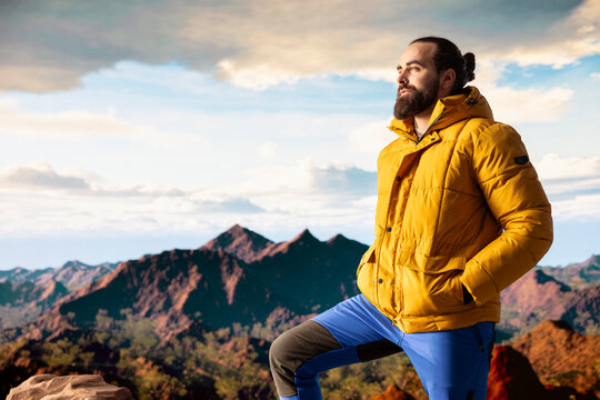 Young adventure seeker looking out at a scenic mountain range view from the top, embracing the solitude and fresh air of the nature wilderness. Sense of mindfulness and exploration.