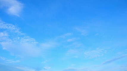 A Timelapse video of clear blue sky with light, wispy clouds scattered across. The overall tone is calm and serene, evoking a sense of peace and openness.
