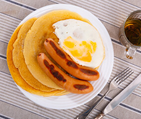 Simple and hearty home food, breakfast or lunch. Pancakes, fried chicken egg and sausage are served on plate. Food blogger, stories