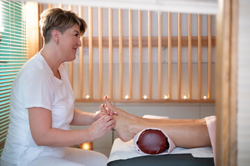 Foot Massage Therapy in a Relaxing Spa Setting. A professional massage therapist in a white uniform...