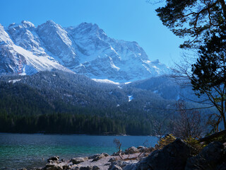 Majestic snow-capped mountains reflected in shimmering lake under clear blue sky
