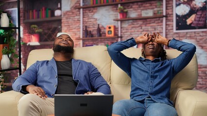 African american couple laying back on the couch and relaxing, feeling extremely tired and working...