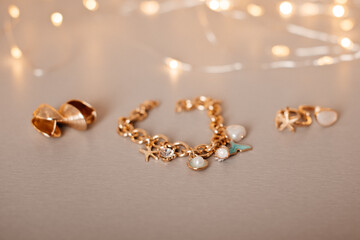 A delicate gold charm bracelet with pearl and gemstone accents, elegantly placed against a warm bokeh background.