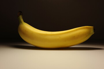 Minimalist photo of a single ripe banana on a neutral background. Soft shadows and warm lighting...