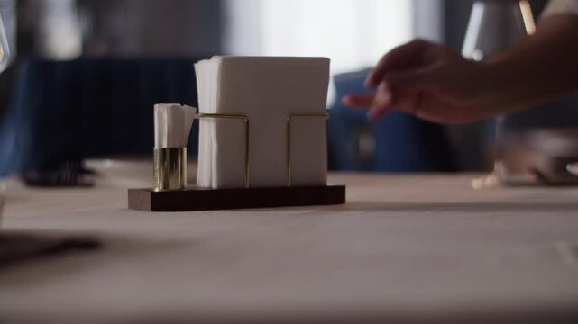 Server putting napkin tray with toothpicks on table