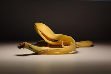 Minimalist photo of a peeled banana with the skin elegantly curled on a neutral background. Soft...