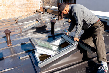 Roofer installing a new roof window. Installation and assembly of new roof windows as part of a...