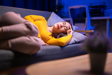 A woman is laying on a couch with her head on a pillow