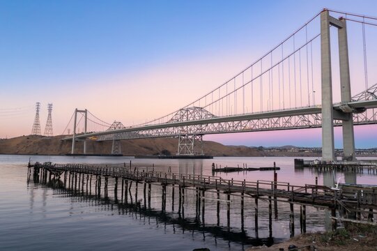 The Alfred Zampa Memorial Bridge spans the Carquinez Strait in California, USA, connecting Contra Costa and Solano counties. An old pier sits in the foreground.