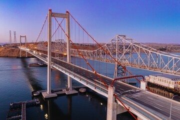 Obraz premium The Alfred Zampa Memorial Bridge carries vehicles across the Carquinez Strait in Crockett, California, USA. The image shows the bridge at dusk with light trails from cars.
