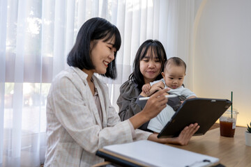A woman is holding a tablet and a baby is sitting on her lap