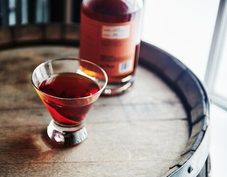 Whiskey cocktail sitting on top of an old whiskey barrel 